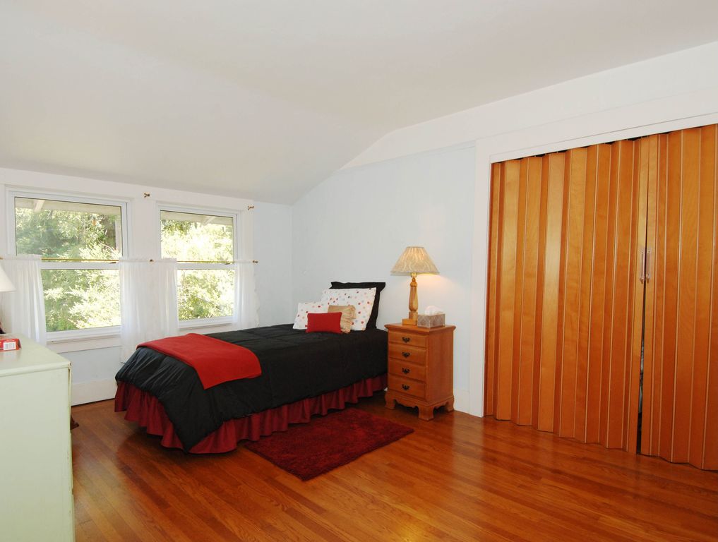 Traditional Guest Bedroom with double-hung window, Hardwood floors, Standard height, Built-in bookshelf