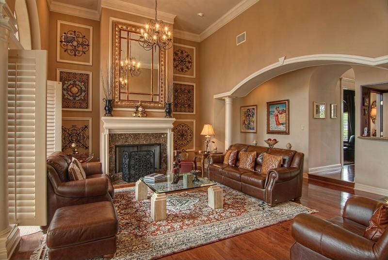 Mediterranean Living Room with metal fireplace, High ceiling, Columns, stone fireplace, Chandelier, can lights, Crown molding