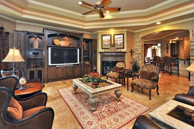 Traditional Living Room with Built-in bookshelf, stone tile floors, Standard height, Fireplace, Ceiling fan, Crown molding